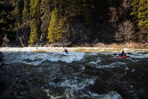 Mountain river turbulent flow, kayaking on the waves, athletes kayakers swim along the mountain river among the rocks, water tourism, kayak, powerful stream, barrel. photo