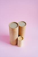 Craft tubes of different sizes stand on a pink background. Cardboard boxes for pencils. Packing set. subject survey of packaging goods photo