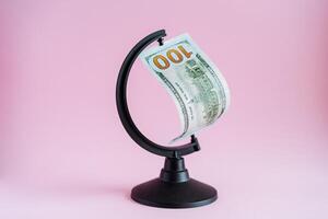 An unusual shot of a globe with one hundred dollars. Creative set design with currency. The dollar is a world currency. Wealth photo