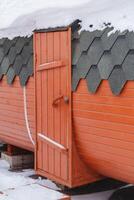 Wooden door entrance to the bathhouse of round shape. Sauna barrel part of the building side view. photo