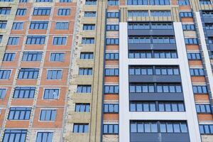 el fachada de el edificio tiene ventanas en un ladrillo pared. aislamiento de un residencial edificio, térmico aislamiento mineral lana, un estante de un residencial edificio, frente a el fuera de foto