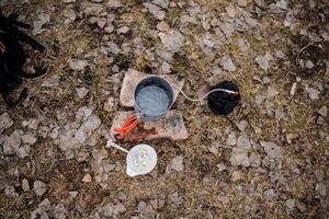 Water boils in a pot, tourist utensils, camp cooking on a hike, spring trekking through the forest, a top view of the camp kitchen. photo