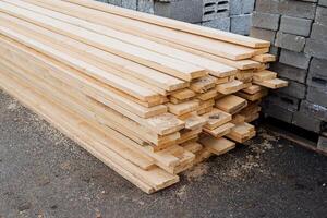 The planks for construction are shot close-ups, the building materials are wooden planks, the pine board lies on the ground in a heap. photo