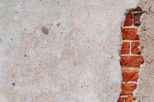 Minimalistic frame of the wall. Through the cement covered brickwork can be seen. Crack with the brick wall. Textured surface. Red brick wall photo