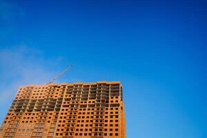 un casa debajo construcción en contra un azul cielo. el concepto de urbano arquitectura. futuro residencial Departamento edificio. foto