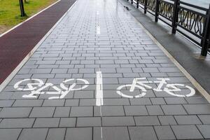 Bicycle path, drawing of a bicycle on the sidewalk, marking of the movement of cyclists on the asphalt in the city park, road sign bicycle photo