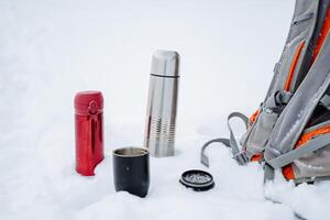 A cup of hot tea from a thermos. Drink coffee in nature. Metal thermal mug made of steel. A bottle that retains heat. Picnic utensils, camping kit. photo