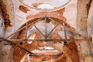 The destroyed vaults of the ancient temple, the Orthodox church are the ruins of the last century, the interior of the church monastery, the walls are made of red brick, the plaster has collapsed. photo