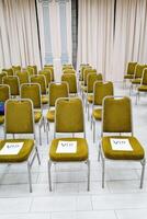 VIP seats in the pen row. Green chairs stand indoors. Business conference in the classroom. Lecture hall. photo