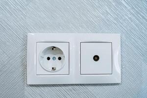 Socket combined with cable socket TV, electrical socket, socket installed on the wall in the room, white design of the panel on the plug of the electrical appliance. photo