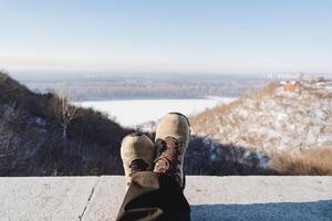 Feet against the background of the forest. The boots are lying on a rock. Foot thrown over foot in nature, minimalism in shoes. photo