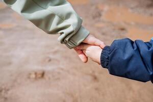 Hands pull each other, an adult holds the child's hand, hold hands together, walk in nature, hands on a brown background, mother and son. photo