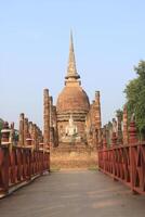 Buddha statue in front of ancient pagoda in  Sukhothai Historical Park photo