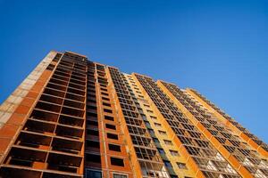 Fragment of a building without windows, construction site. The facade of the house is made of red brick. Construction against the sky. photo