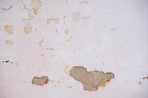 Textured surface of the city wall. Plaster flying around. Holes in the wall. Renovation of living quarters photo