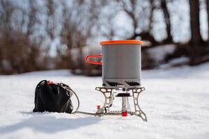 The pan stands on the gas burner shot close-up, the dishes hike tourism, the gas goes through the hose to the burner, the pot with the lid, the gray color of the metal. photo