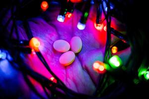 Happy New Year background for greeting card. snowman candlestick close-up with festive garland. Against the background of colored lights. High quality photo