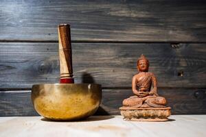 A Tibetan singing bowl and statue of Buddha on the floor. A subject for meditation and healing sounds. Zen practice.Calm and tranquillity photo