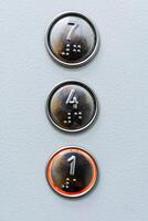 un aproximado Disparo de Tres ascensor botones. Siete, cuatro, uno. ardiente ascensor llamada botón. fuente para el ciego en el ascensor panel foto