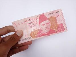 pakistaní 100 Nota sostener en mano, aislado en blanco fondo, eso es el local moneda de el Pakistán. foto