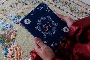 Close up view of a muslim woman holding the Quran or surah yaseen or yasin book photo