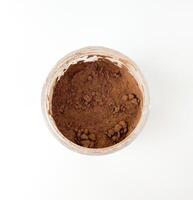 cacao oscuro chocolate marrón polvo bebida dentro claro frasco. objeto fotografía desde parte superior ver aislado en blanco llanura antecedentes. foto