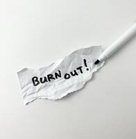 Burn out stressed out saying from tiredness of working handwriting with black marker isolated on crumpled ripped off paper on white background. photo