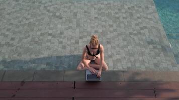 caucasian kvinna arbetssätt avlägset på de dator medan Sammanträde i simning slå samman video