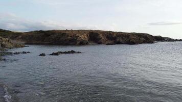 el silueta de el rocas con vista a un pequeño bahía en Cerdeña a puesta de sol en un nublado día. video