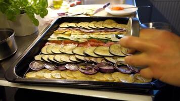 Preparation of mixed vegetables cut into thin slices, oiled and placed in the pan to be baked. Aubergines, tomatoes, potatoes, courgettes and red onions video