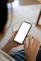 Mockup smartphone of a woman holding and using mobile phone with blank screen while on the sofa with feeling relaxed photo