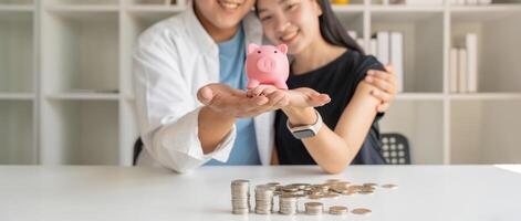 Happy couple asian saving while sitting together on desk at home, loving spouse plan budget and saving money for future photo