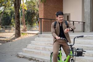 Asian businessman in a suit is riding a bicycle on the city streets for his morning commute to work. Eco transportation concept, sustainable lifestyle concept photo