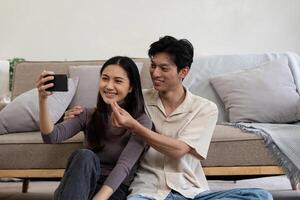 Happy couple asian young women happy smile and taking selfie on couch in living room at home photo