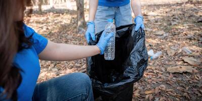 Young people friend volunteer collecting garbage plastic bottles to trash bags. environmental care ecology concept photo