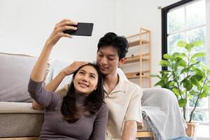 Happy couple asian young women happy smile and taking selfie on couch in living room at home photo