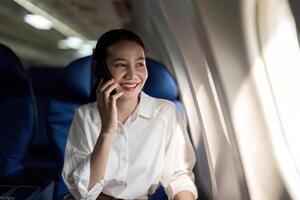 Traveling and technology. Flying at first class. Young business woman passenger using smartphone while sitting in airplane flight photo