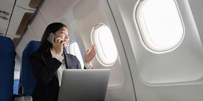 Successful young asian business woman sits in airplane cabin plane and working from anywhere. Flying at first class photo