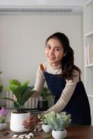 The concept of eco friendly housing, plant care and gardening. Preparing garden. Relax home gardening. Gardener woman asian hand planting flower in pot. Smiling woman takes care of plant photo