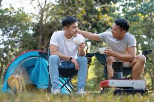 masculino gay Pareja asiático de viaje con tienda cámping al aire libre y varios aventuras estilo de vida excursionismo activo verano vacaciones. Bebiendo café y hablando juntos foto