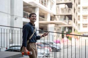 Smiling asian businessman walking to work while to hold reusable eco friendly ecological cup in the city photo