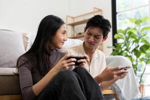 Happy couple asian young women happy enjoy playing match game online game happy relax smile laugh joy fun video gaming app. on couch in living room at home photo