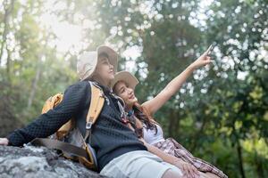Cheerful romantic lesbian couple traveler with backpacks on their backs go hiking through the forest and siting relaxing while hiking in the mountains in summer photo