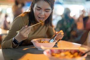 Traveler Asian woman enjoy eating noodle at night market. traditional Chiang Mai Thailand street food. photo