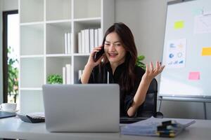 Happy confident businesswoman talking on the phone. Smiling female business person talking work using talking on the phone at office sitting at desk photo