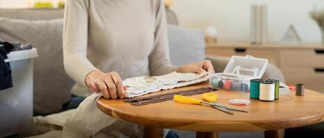 Woman repairs sews reuses fabric from old clothes economical reuse. DIY Hobby Reuse Recycling at home photo