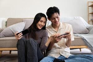 Happy couple asian young women happy enjoy playing match game online game happy relax smile laugh joy fun video gaming app. on couch in living room at home photo