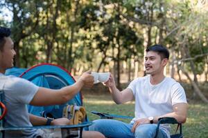 Male gay couple asian traveling with tent camping outdoor and various adventure lifestyle hiking active summer vacation. drinking coffee and talking together photo