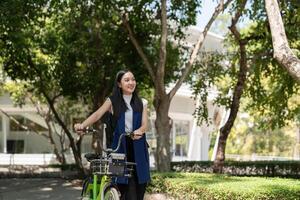 Asian businesswoman in bicycle go to work at office. Bike commuting, happy businesswoman using eco transport, Concept of eco lifestyle photo