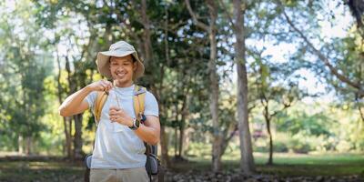 Traveler hiking man carrying a backpack on the back and walking in national park. man asian is rest by drink water photo